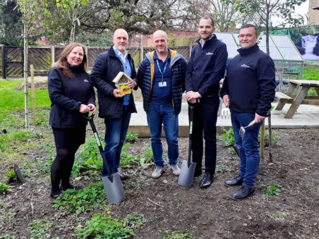 Five people stood with gardening equipment in the new beginning's allotment